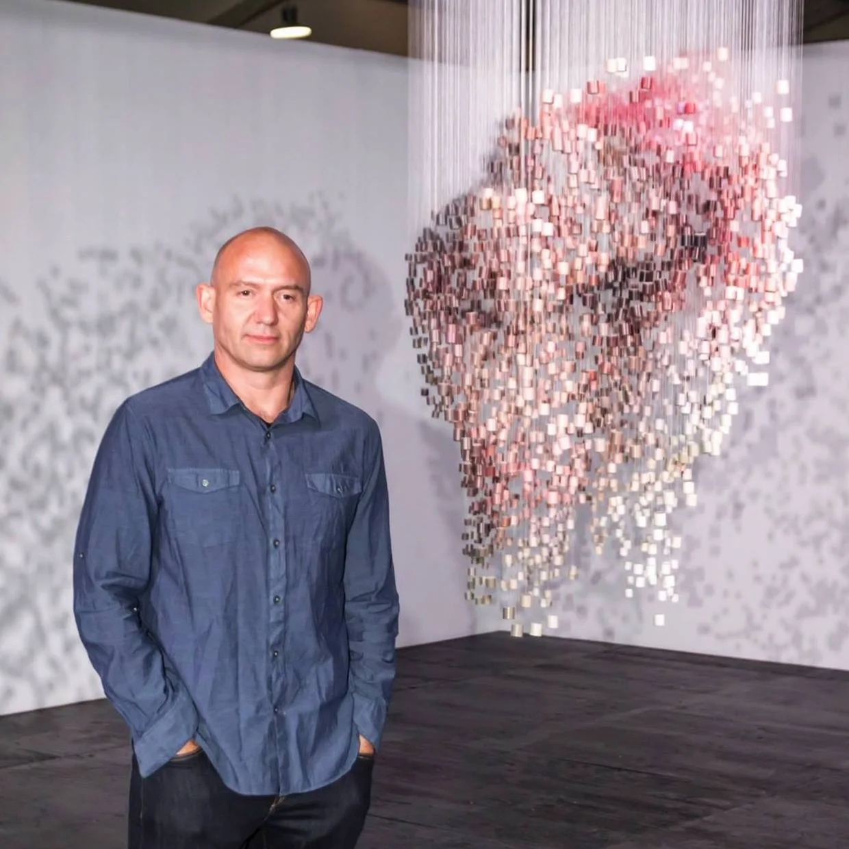Michael Murphy standing beside a suspended anamorphic portrait sculpture